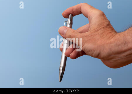 silver brushed steel ballpoint pen in a mans hand, clicking on and off. Stock Photo