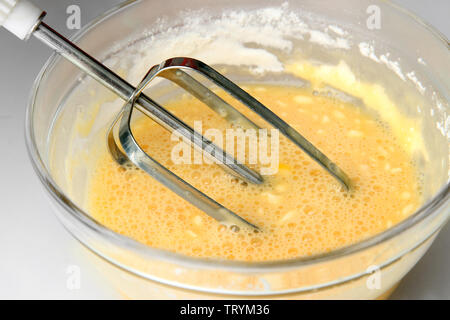 Cooking, whipping eggs with electric whisk in bowl, close up Stock Photo