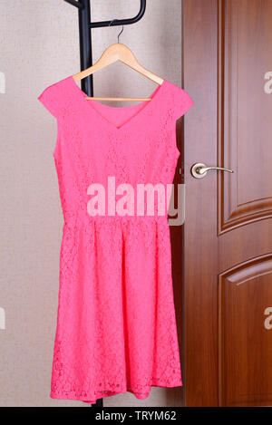 Dress hanging on hanger near door Stock Photo