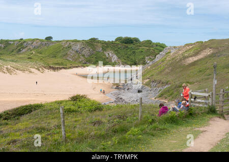 Group of walkers having a picnic along the Pembrokeshire coast path at Broad Haven in Pembrokeshire, Wales Stock Photo