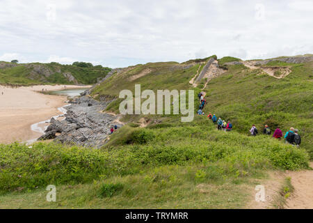 Group of walkers hiking along the Pembrokeshire coast path at Broad Haven in Pembrokeshire, Wales Stock Photo