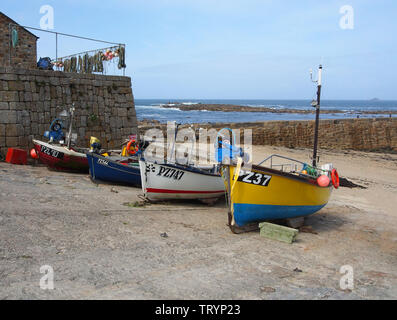 A group of very colourful fishing boats hauled up on to the quay at Sennen Cove, Cornwall, England, with the blue sky and blue sea in the background. Stock Photo