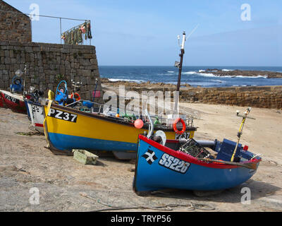 A group of very colourful fishing boats hauled up on to the quay at Sennen Cove, Cornwall, England Stock Photo