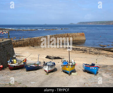 A colourful array of boats hauled up on to the quay at Sennen Cove, Cornwall, England, with the blue sky and blue sea in the background. Stock Photo
