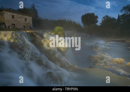 Night view of the famous free spa of the mill in Saturnia in Tuscany, Italy. A series of natural pools of hot water where people relax Stock Photo