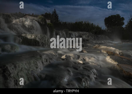 Night view of the famous free spa of the mill in Saturnia in Tuscany, Italy. A series of natural pools of hot water where people relax Stock Photo