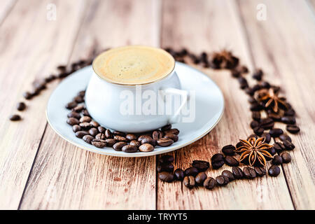 Close-up view of a cup of hot coffee on wooden rustic table with spilled coffee beans and anise. Space for text . Stock Photo