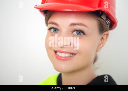 Young smiling caucasian woman wearing red safety hard hat, close up Stock Photo