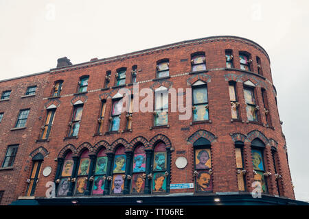 Dublin, Ireland - September 2018. Facade of a large red brick building with colorful posters on the windows. Stock Photo