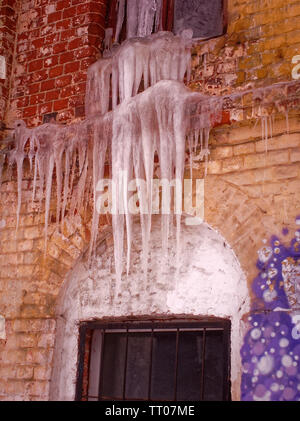 large icicles hanging from an old brick house, Russia Stock Photo
