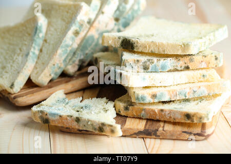 Mouldy bread on cutting board, on wooden background Stock Photo