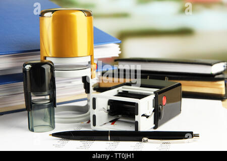 Stamps with notepads and papers on table on bright background Stock Photo
