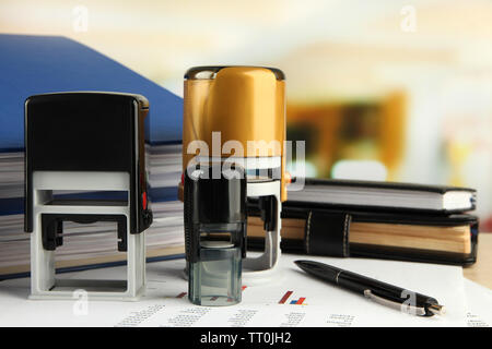 Stamps with notepads and papers on table on bright background Stock Photo