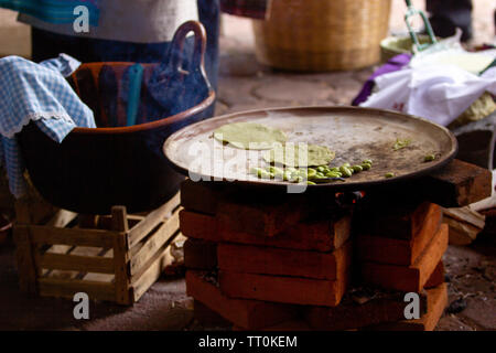 cooking tortillas on a mexican three stone stove fired by wood, mole and broad beans, rural scene Stock Photo