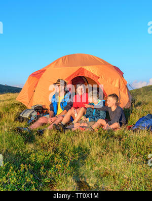 Family enjoys evening sun in front of a tent Stock Photo