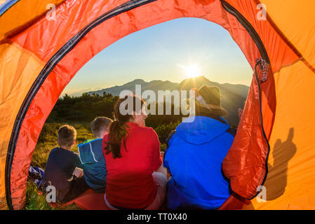 Family enjoys evening sun in front of a tent Stock Photo