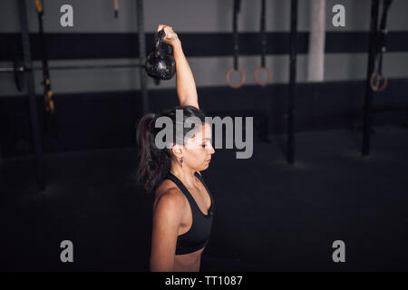 Young woman realizing indoor exercises with kettlebell Stock Photo