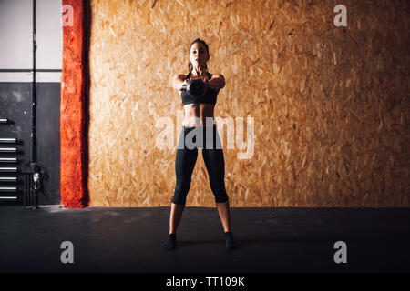 Young woman realizing indoor exercises with kettlebell Stock Photo
