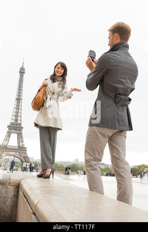 Happy, romantic young couple tourists having fun in Paris. Man photographing woman near the Eiffel Tower. Stock Photo