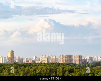 sky with large pink and white cumulus clouds over modern residential houses in city in summer twilight Stock Photo