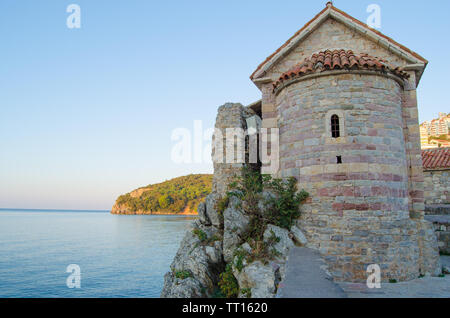 Round tower with red tiled roof at the wall of the old town, against the sea in the morning. Stock Photo