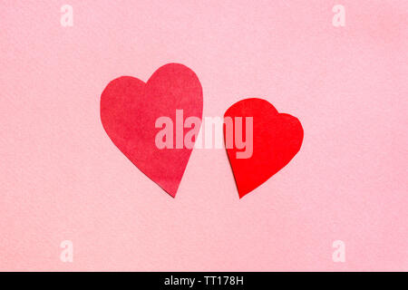 two hearts cut from red paper on pink paper background Stock Photo