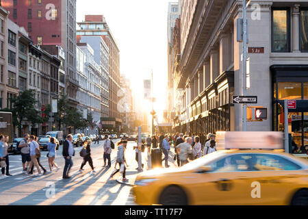 NEW YORK CITY: Yellow taxi cab speeds past the crowds of people at the intersection of 23rd Street and 5th Avenue in Midtown Manhattan NYC Stock Photo