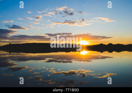 Quiet surface of the river on the background of a colorful sunset.Beautiful landscape of nature.The reflection of the sky. Stock Photo