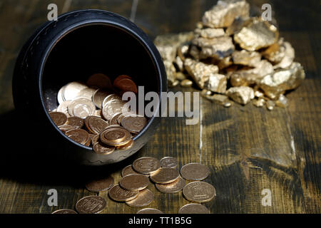 Golden coins falling out from pot, on wooden background Stock Photo