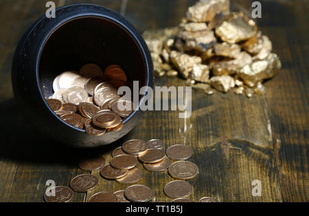 Golden coins falling out from pot, on wooden background Stock Photo