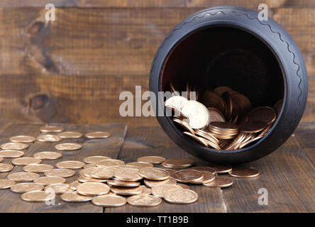 Golden coins falling out from pot, on wooden background Stock Photo