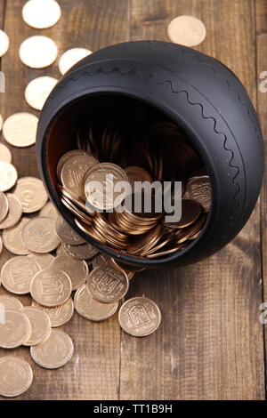 Golden coins falling out from pot, on wooden background Stock Photo