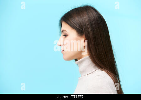 portrait of a young caucasian woman, looking down, side view, isolated on blue background Stock Photo