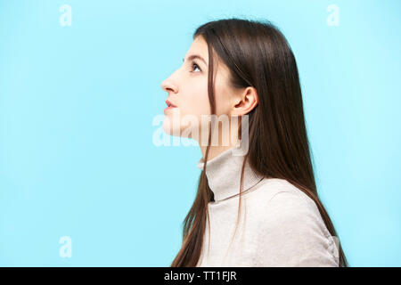 portrait of a young caucasian woman, looking up, side view, isolated on blue background Stock Photo