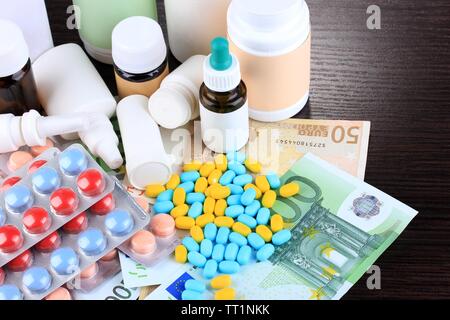 Prescription drugs on money background representing rising health care costs. On wooden background Stock Photo