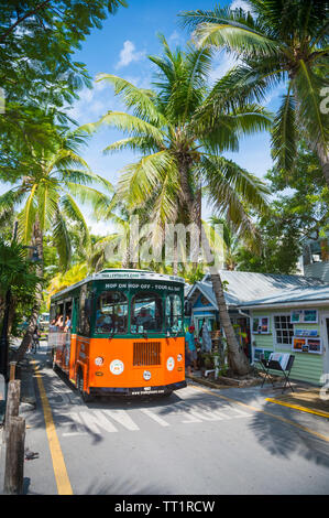 KEY WEST, FLORIDA, USA - SEPTEMBER, 2018: Tourists ride a hop-on hop-off sightseeing bus past the traditional colorful shacks of Old Town. Stock Photo