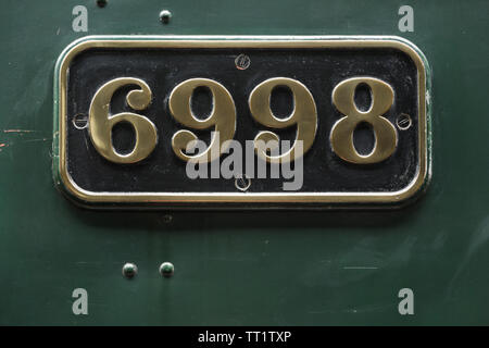 Embossed polished brass number plate sign fixed to green steam engine locomotive number 6998 'Burton Agnes Hall' at Didcot Railway Centre, Oxfordshire Stock Photo