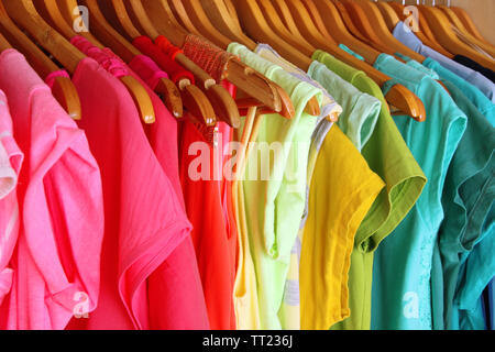 Colorful clothes on hangers in wardrobe Stock Photo