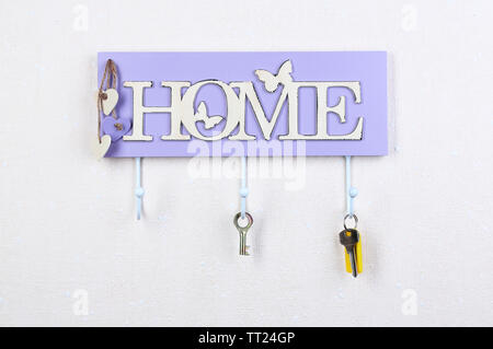 Keys hanging from hooks, on light wall background Stock Photo