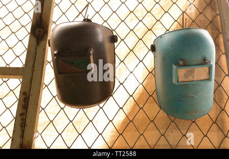 Closeup of welding masks hanging on the fence of working area, safety concept Stock Photo