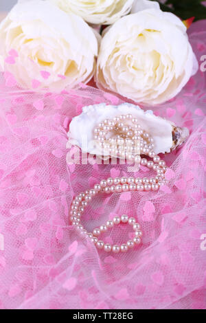 Beautiful pearls in shell on pink cloth Stock Photo