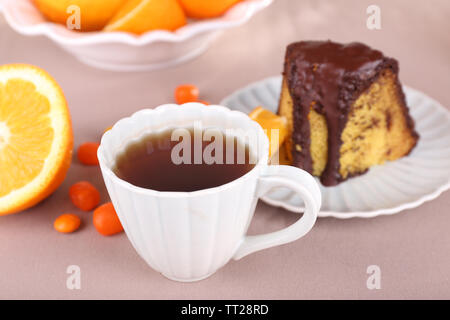 Piece of delicious cake  with oranges on tablecloth close-up Stock Photo
