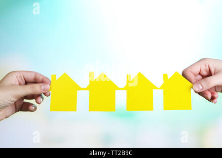 Hands hold houses on grass on natural background Stock Photo