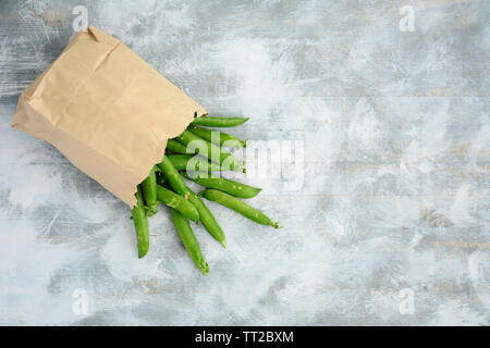 Fresh from the garden organic English peas in brown paper bag on rustic wooden background.  In flat lay composition, horizontal format with room for t Stock Photo
