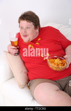 Lazy overweight male sitting on couch and watching television Stock Photo