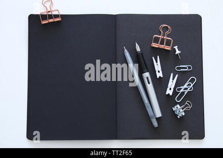 White office desk table with open notebook with empty pages and other office supplies. Top view Stock Photo