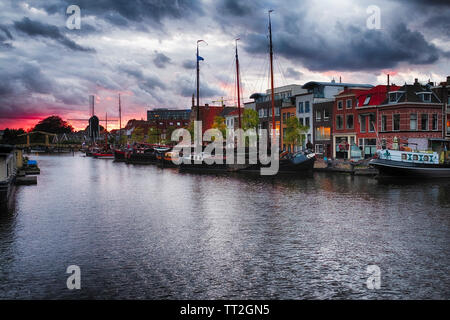 Canal woth Old Ships a Windmill and a Drawbridge at Sunset, Leiden, Netherlands Stock Photo