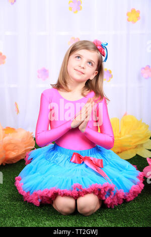 Beautiful small girl in petty skirt on decorative background Stock Photo