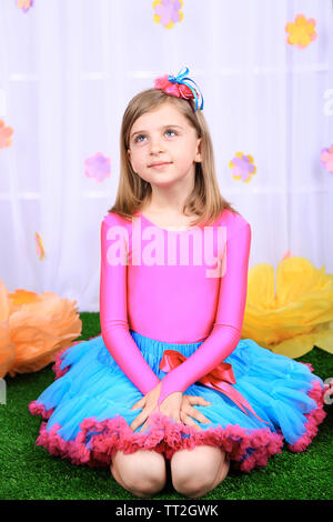 Beautiful small girl in petty skirt on decorative background Stock Photo