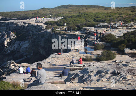 People sitting and watching view on rocky cliff top Stock Photo